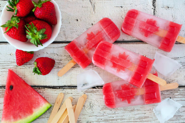 Canadian flag popsicles, top view on a rustic white wood table. Canada Day food concept.