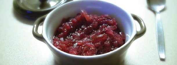 a bowl filled with redberry relish with a spoon beside it