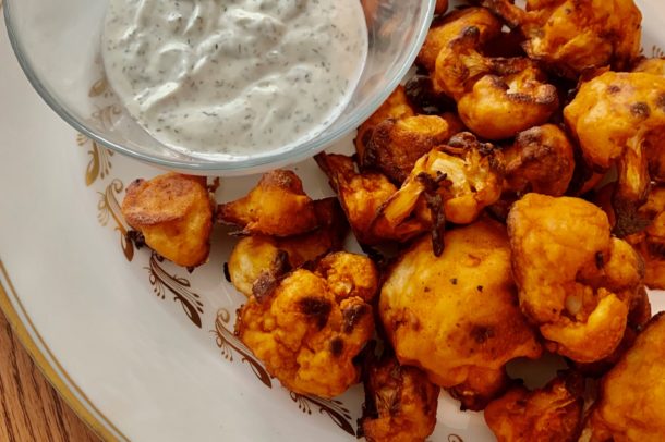 Image of a plate with cauliflower bits and a small dish of sauce