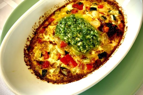 a serving plate of baked eggs with basil pesto