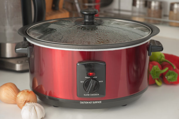 a picture of a slow cooker pot on a counter surrounded by eggs and garlic