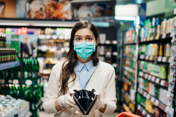 Stressed woman with mask shopping in grocery store with an empty wallet.Bankruptcy/recession.Covid-19 quarantine lockdown impact.Unemployed person in money crisis.Financial hardship.No income anxiety