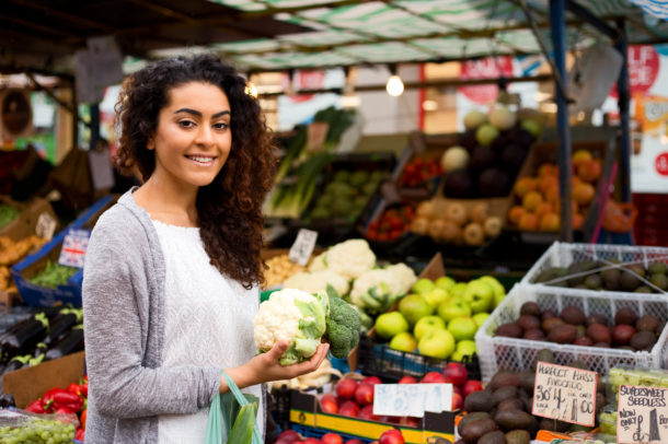 young woman shopping at the market holding a cauliflower