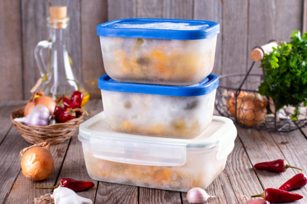 A stack of containers with frozen food on a wooden table