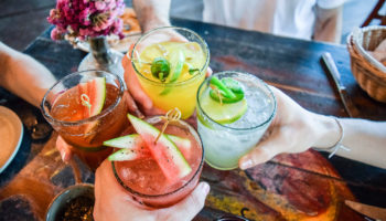 Hands holding tropical cocktails and toasting