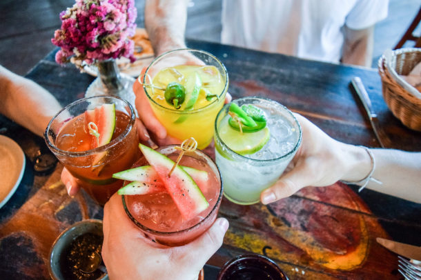 Hands holding tropical cocktails and toasting