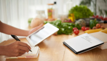 Hands of woman composing healthy menu for upcoming week