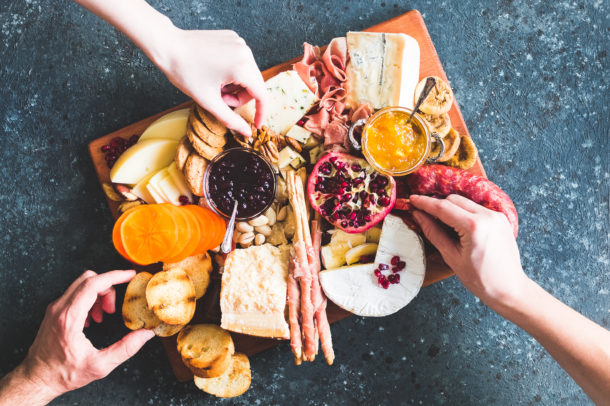 Charcuterie board. Cheese platter: Parmesan, caciocavallo, camembert and other with prosciutto, salami, fruits and nuts. Assortment of tasty appetizers or antipasti. Top view.