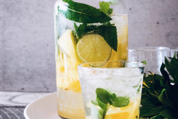 a pitcher and glass on a serving plate filled with lime and mint and sparkliing soda