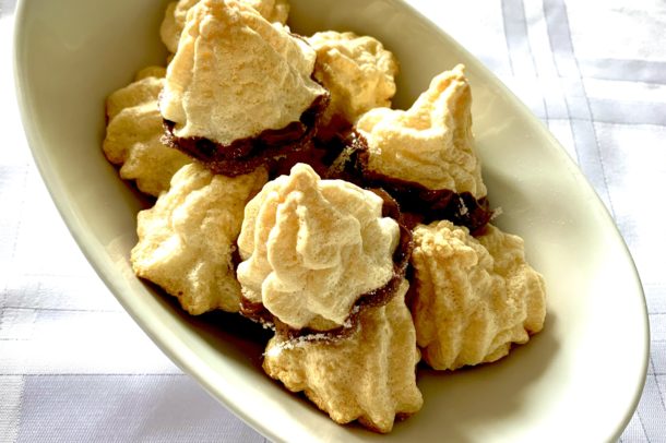 a white bowl filled with meringue cookies dipped in chocolate