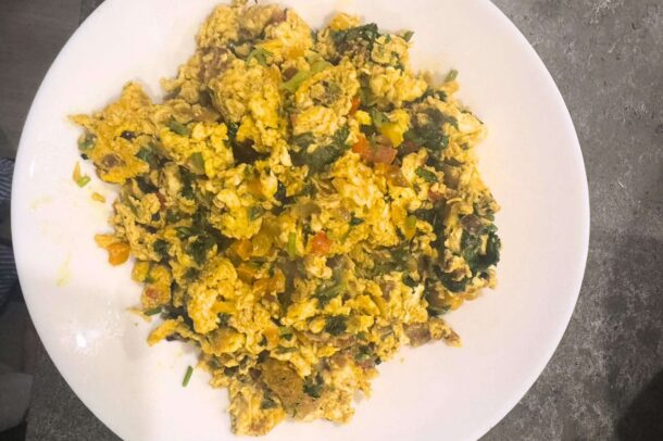 Œufs brouillés cuits avec des légumes hachés et des herbes, servis dans une assiette blanche