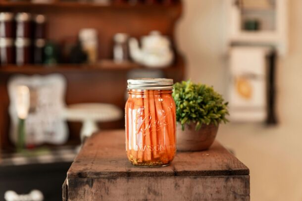 Jar of pickled carrots on wooden table in cozy kitchen