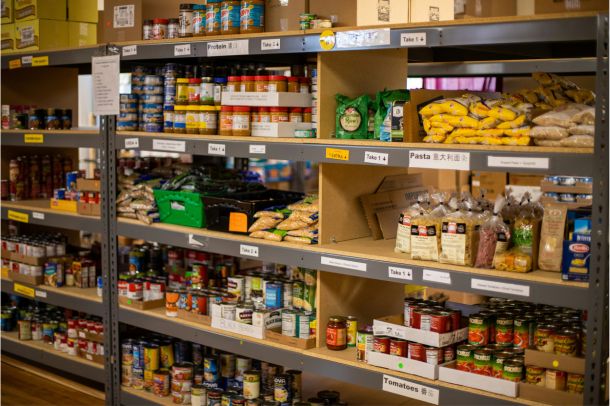 Des étagères remplies de conserves, de pâtes et de produits emballés dans une banque alimentaire.